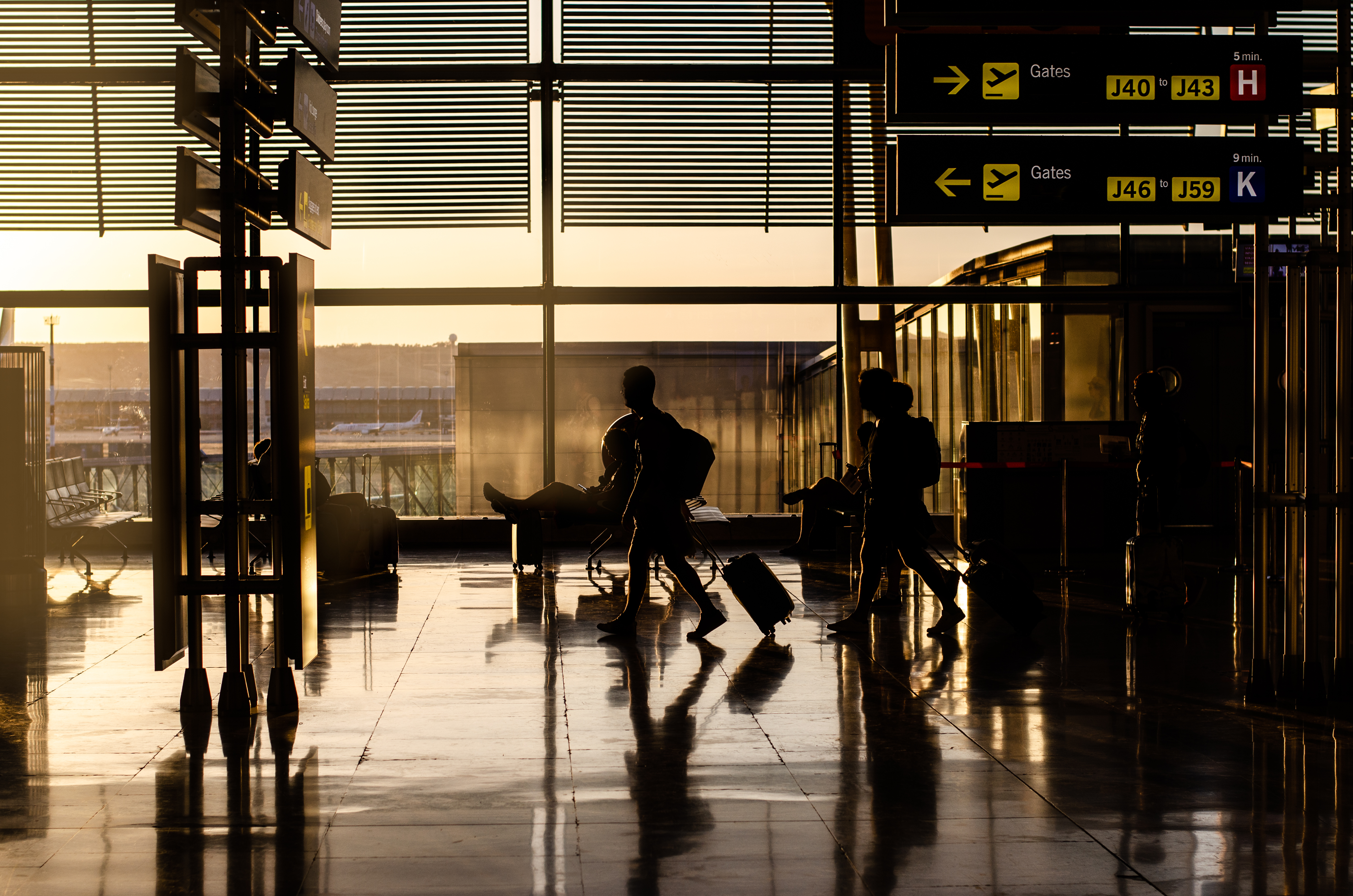 Putnici s koferima ispred ulaza u terminal zračne luke u rano jutro